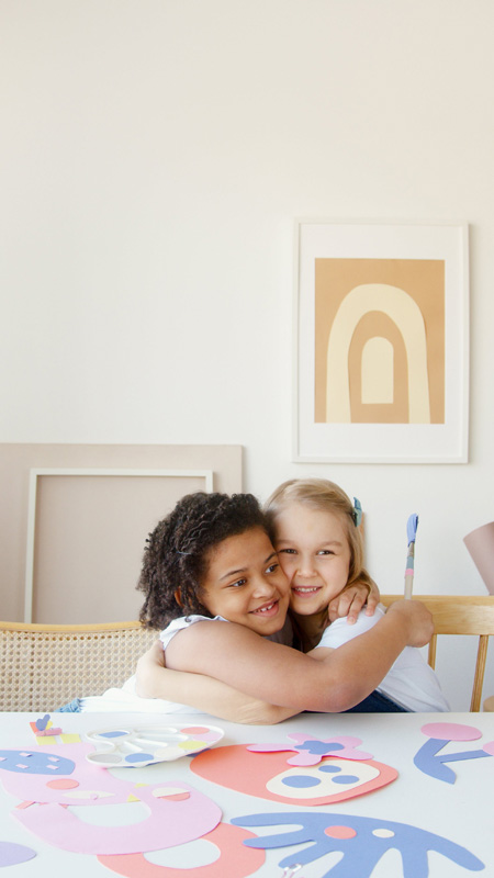 young children at craft table hugging